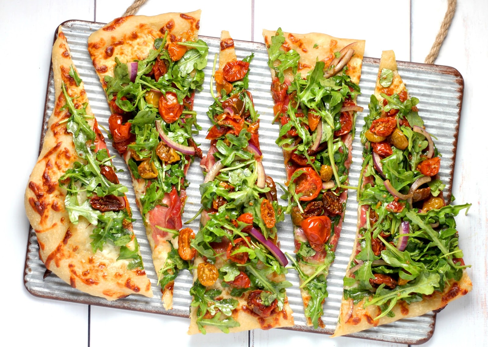 Flatbread pizza with arugula, tomatoes, and red onion
