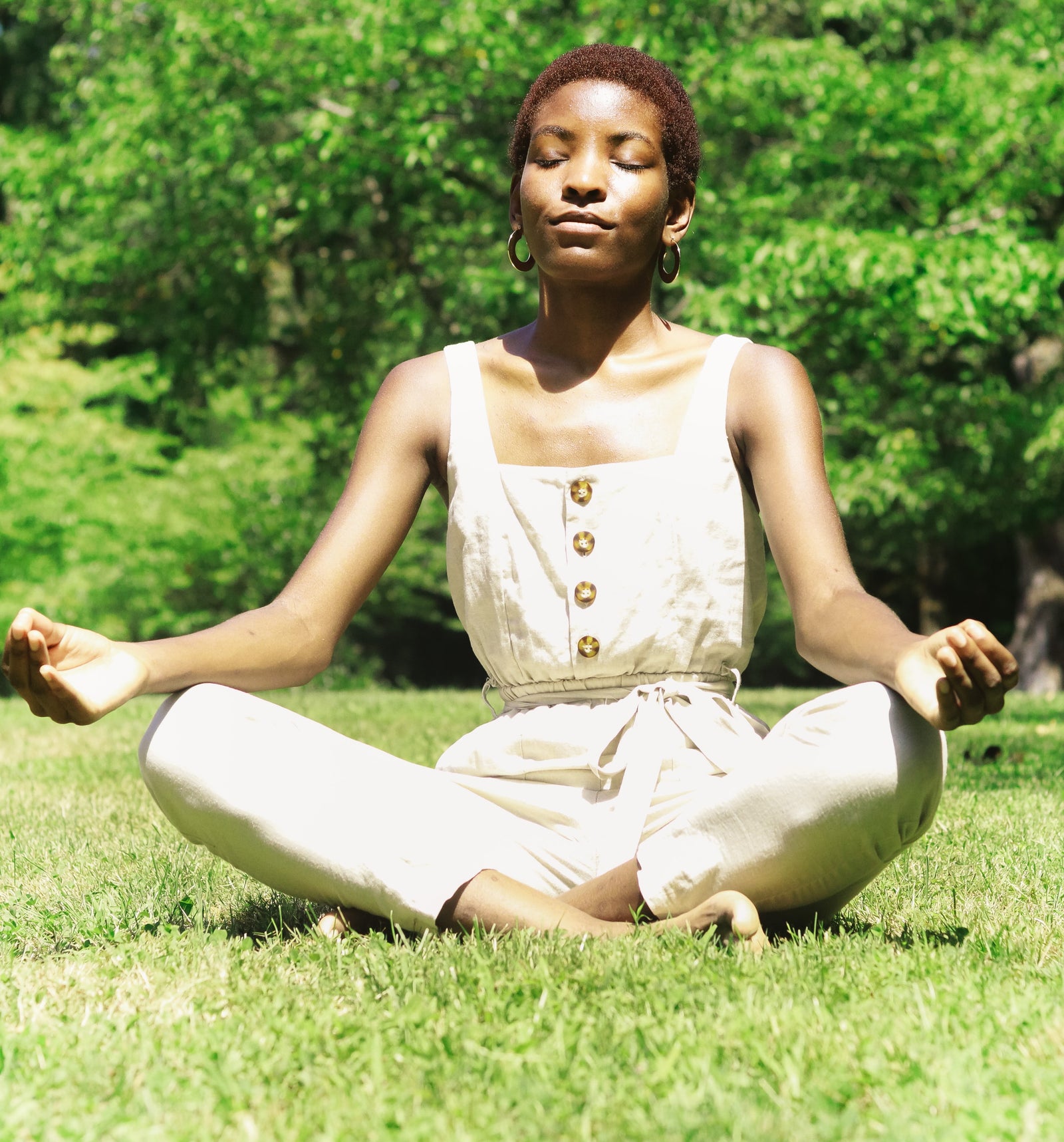 woman sitting in a field meditating in a white jumper